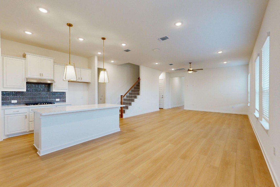 3944 Fulton Drive Leander, TX 78641 - Photo 7 of 23 a large kitchen with kitchen island a stove a sink a refrigerator and white cabinets