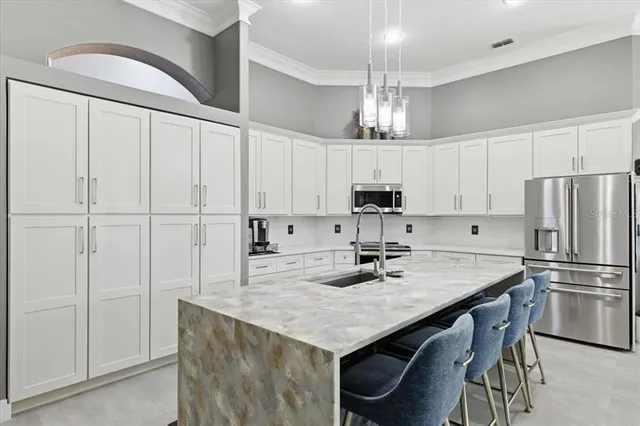 a kitchen with stainless steel appliances granite countertop a refrigerator a sink dishwasher a stove and white cabinets with wooden floor