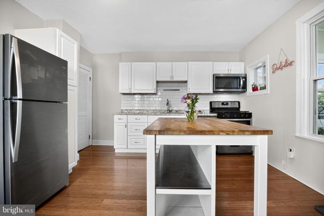 a kitchen with kitchen island granite countertop a refrigerator stove top oven and sink
