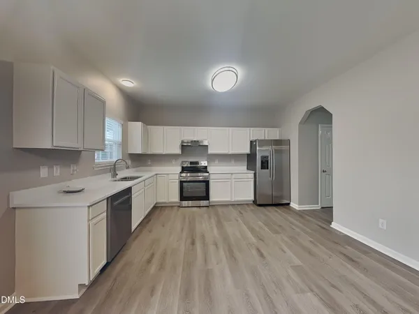 a kitchen with a white cabinets and wooden floor