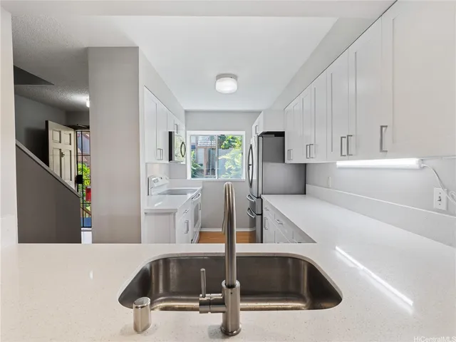 a kitchen with kitchen island a sink a stove and white cabinets