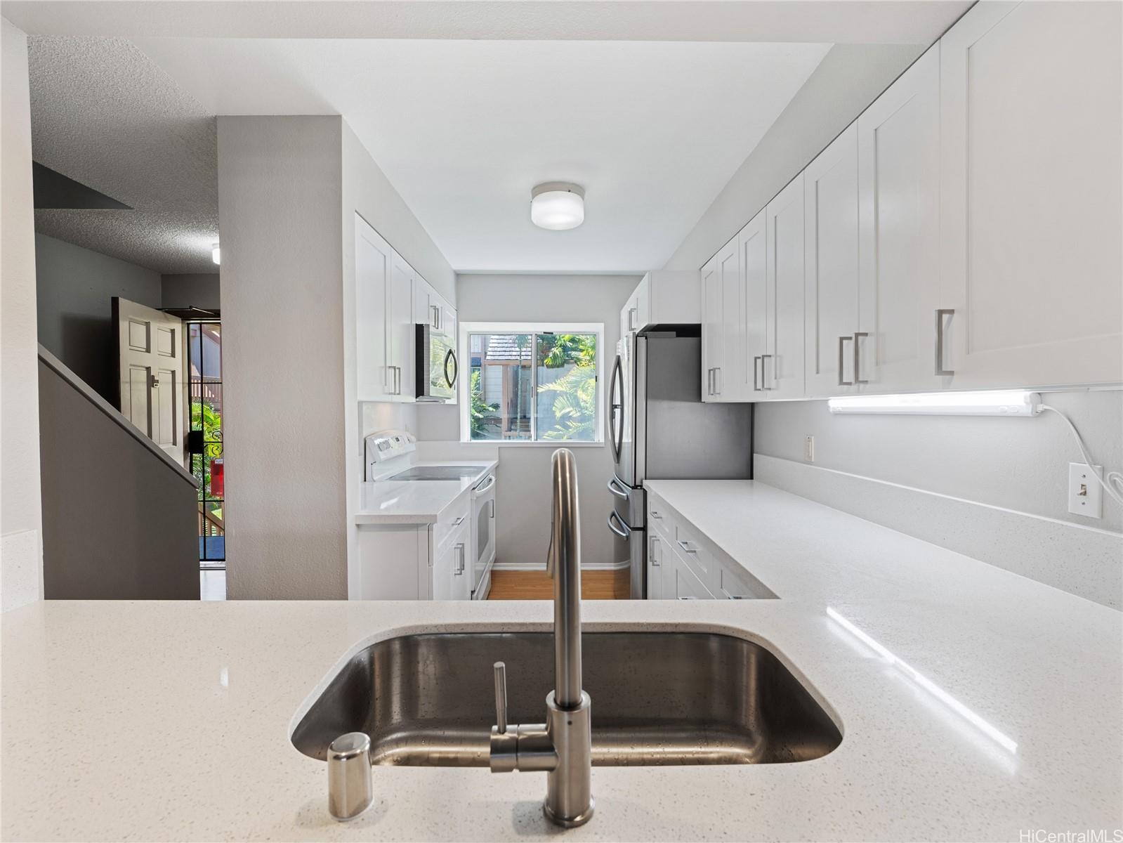 a kitchen with kitchen island a sink a stove and white cabinets