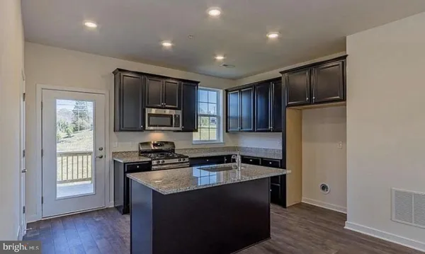 a kitchen with granite countertop stainless steel appliances a refrigerator stove and microwave