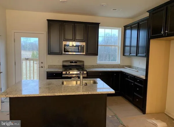 a kitchen with a sink a stove a refrigerator cabinets and a window