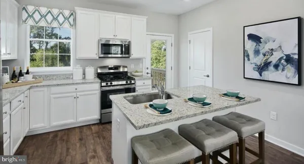 a kitchen with stainless steel appliances granite countertop a stove a sink a microwave a dining table and chairs with wooden floor