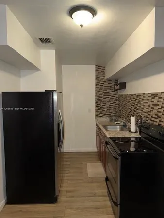 a kitchen with granite countertop a refrigerator and a sink
