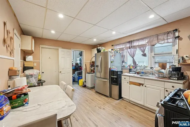 a kitchen with a refrigerator a sink dishwasher a dining table and chairs with wooden floor