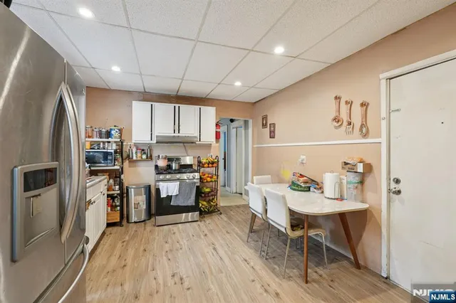 a kitchen with a refrigerator a stove top oven a sink dishwasher and white cabinets with wooden floor