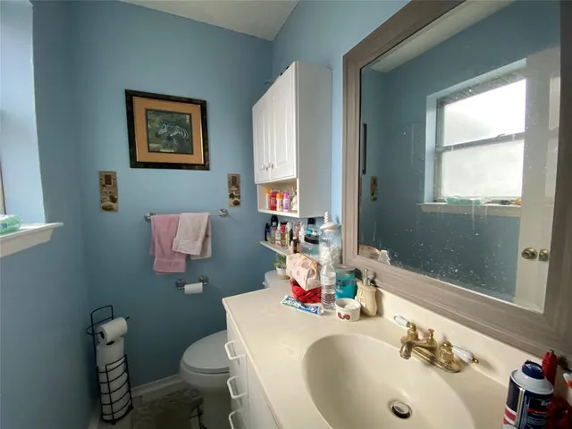 a bathroom with a granite countertop toilet sink and mirror