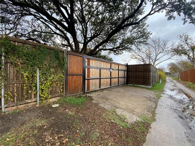 a view of backyard with large tree and wooden fence