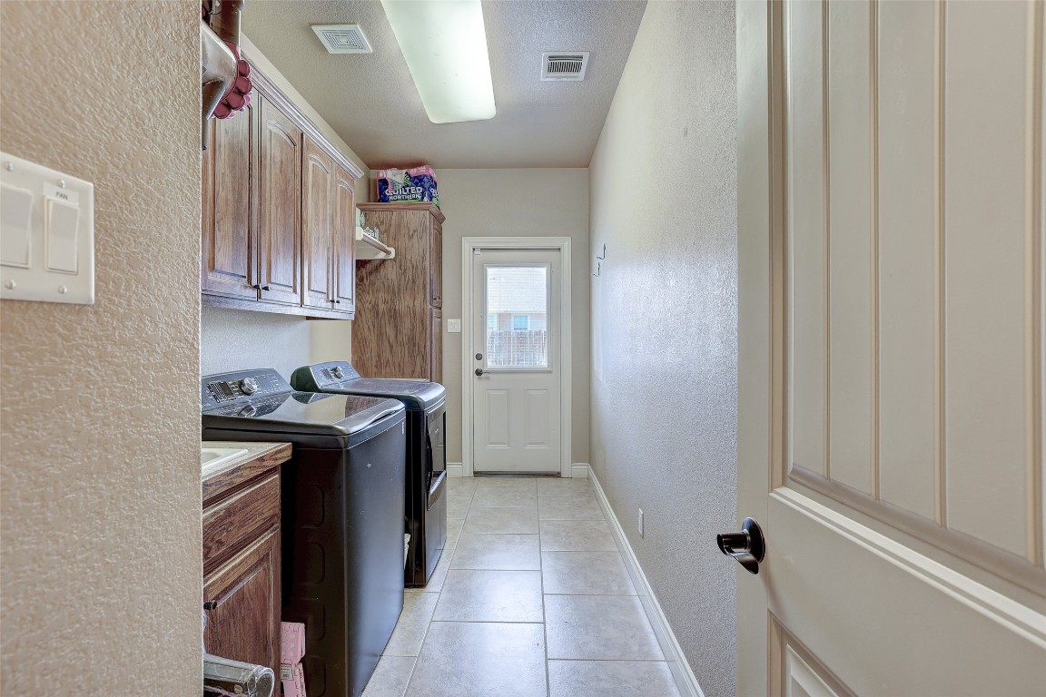 Undisclosed Address Georgetown, TX 78633 - Photo 28 of 38 Laundry area with a textured wall, light tile patterned floors, washing machine and clothes dryer, and cabinet space