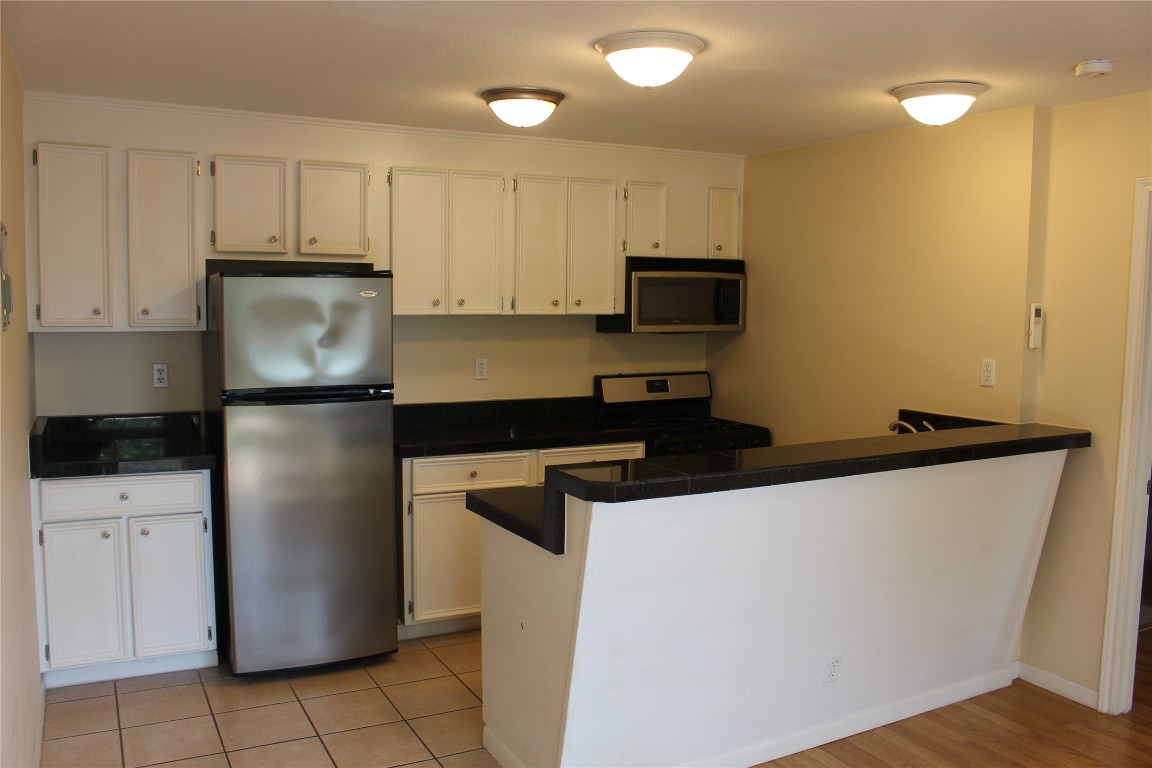 304 East 33rd Street, Unit 19 Austin, TX 78705 - Photo 8 of 15 a kitchen with a refrigerator a stove a microwave and cabinets