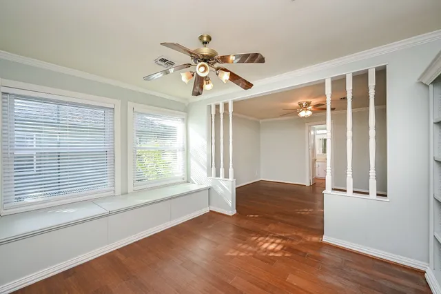 a view of an empty room with window and wooden floor