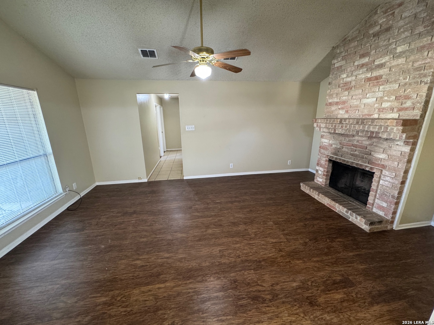 7236 Rimwood Street San Antonio, TX 78233 - Photo 5 of 16 an empty room with wooden floor fireplace and windows