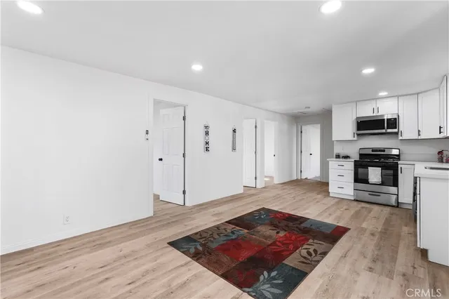 a living room with stainless steel appliances furniture a rug and a wooden floor
