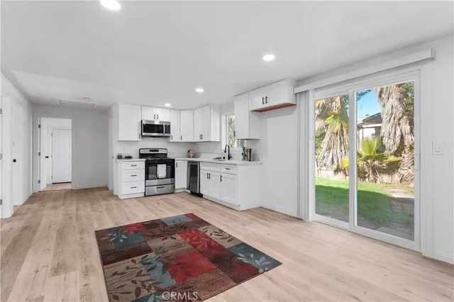 a view of a kitchen with wooden floor electronic appliances and windows