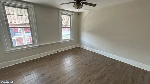 an empty room with wooden floor fan and windows