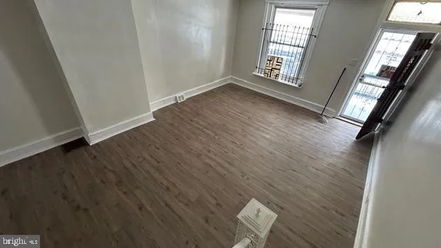 an empty room with wooden floor and windows