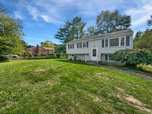 a front view of a house with a garden and trees
