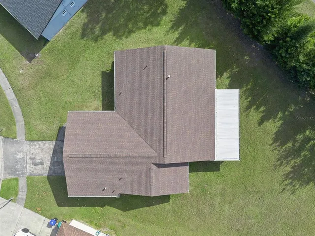 an aerial view of residential houses with outdoor space and trees