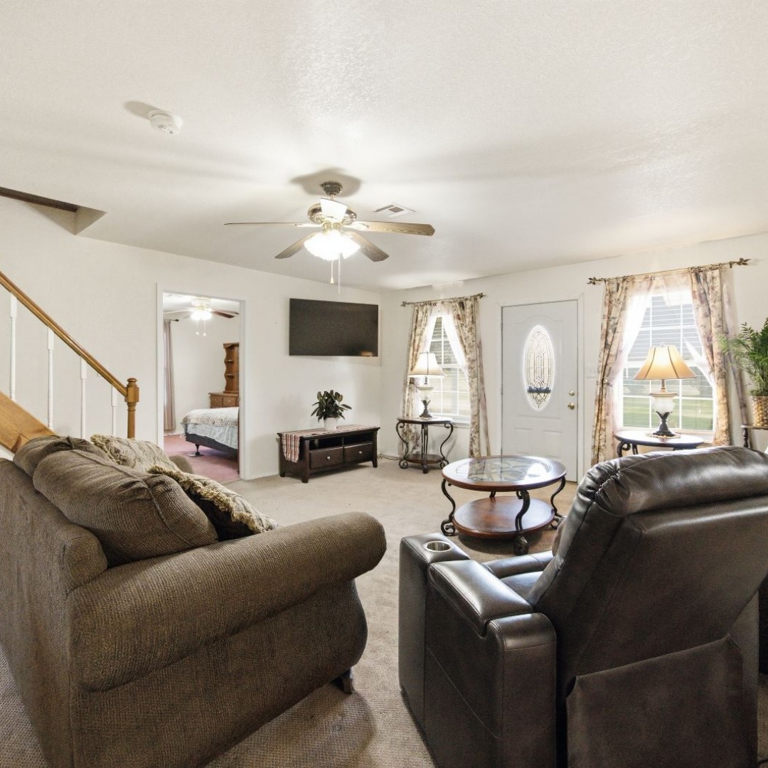 2696 Russellville Road Quinton, OK 74561 - Photo 5 of 40 Inviting living area featuring a ceiling fan with integrated lighting, a white paneled front door with an oval glass insert, and two large windows with decorative valances