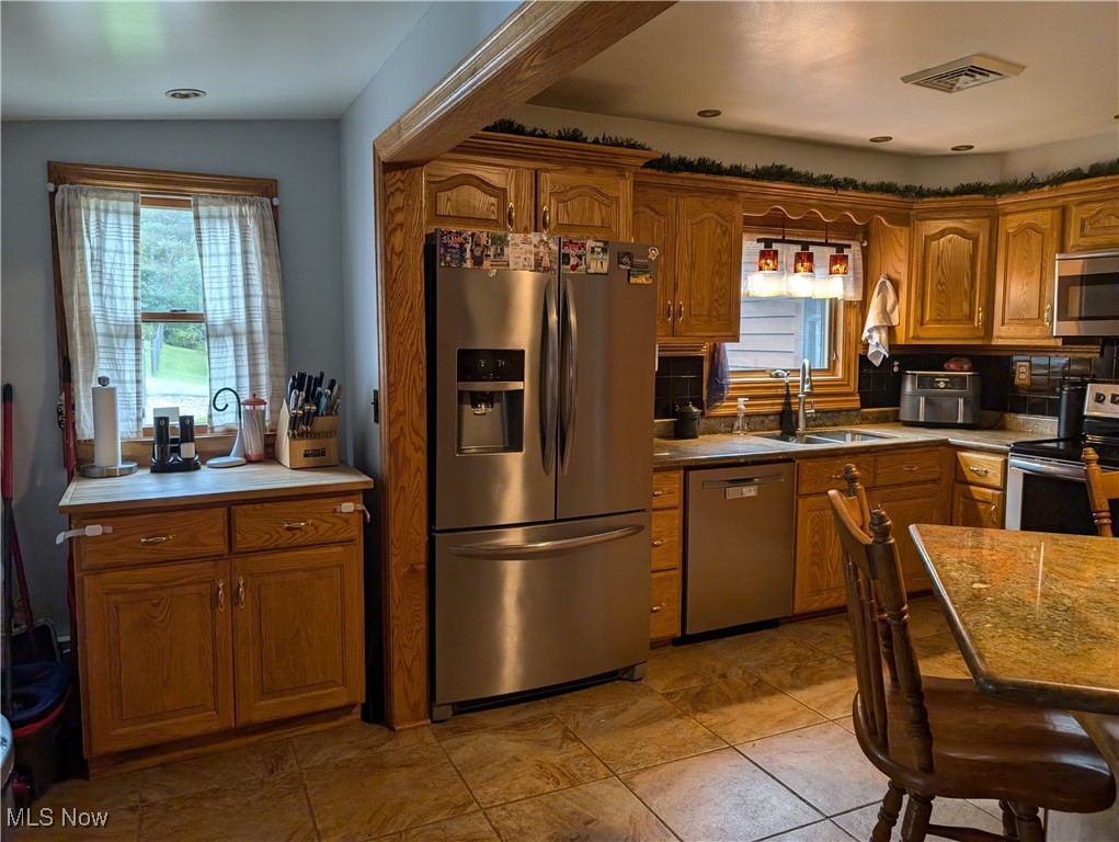 46136 Carlisle Road Lisbon, OH 44432 - Photo 34 of 48 Kitchen with appliances with stainless steel finishes, decorative backsplash, sink, and vaulted ceiling