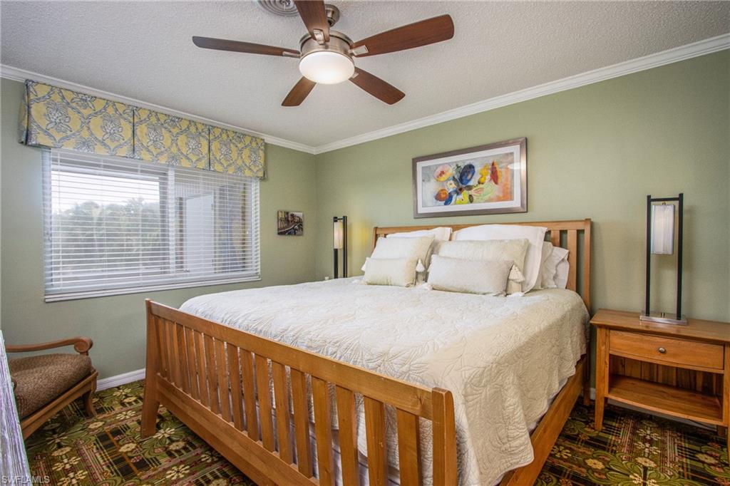 820 Ketch Drive, Unit 8 Naples, FL 34103 - Photo 10 of 16 a bedroom with a bed and a chandelier