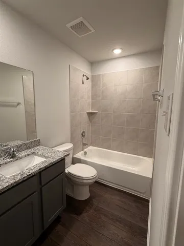a bathroom with a granite countertop sink toilet mirror and bathtub