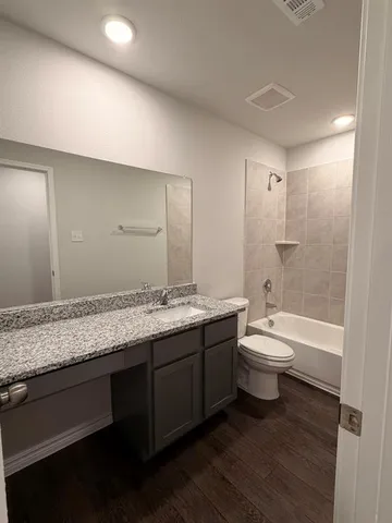 a bathroom with a granite countertop sink mirror vanity and toilet