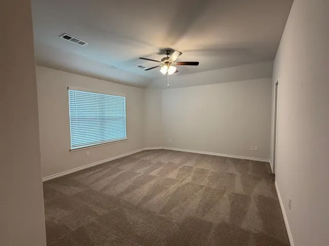 an empty room with windows and fan