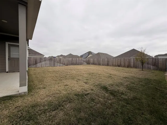 a view of a dry yard with wooden fence