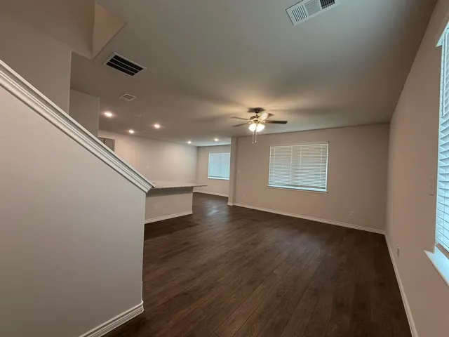 an empty room with wooden floor chandelier and windows