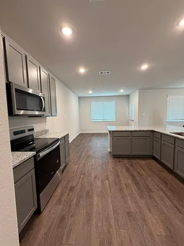 a large kitchen with stainless steel appliances granite countertop a stove a sink dishwasher and a microwave oven with wooden floor