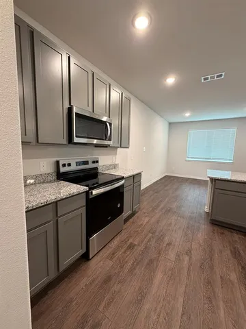 a large kitchen with stainless steel appliances granite countertop a stove a sink and a microwave