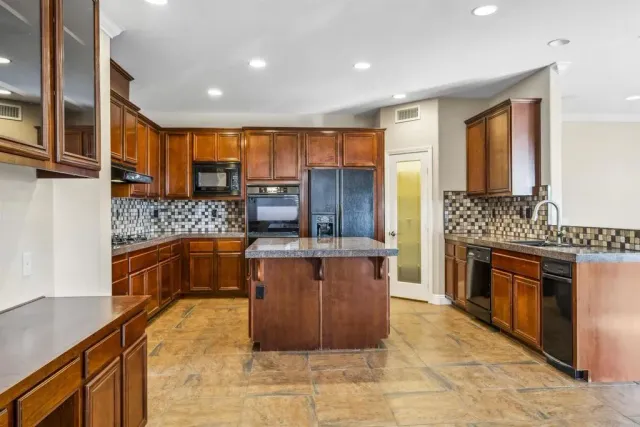 a kitchen with stainless steel appliances granite countertop a stove a sink and a microwave