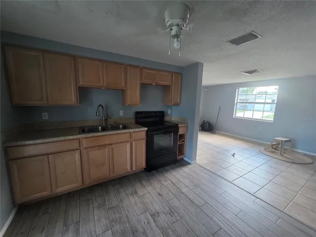 a kitchen with granite countertop a stove a sink a refrigerator and cabinets