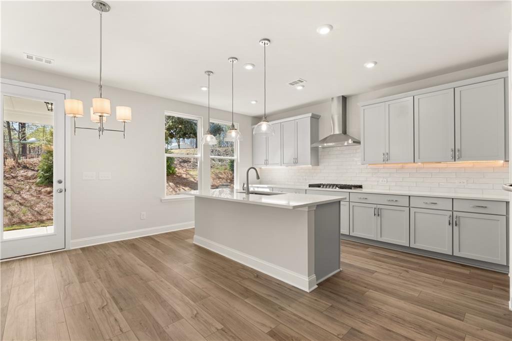 900 Melody Ridge Lane Buford, GA 30518 - Photo 13 of 30 a kitchen with stainless steel appliances granite countertop a sink a stove a refrigerator and white cabinets with wooden floor