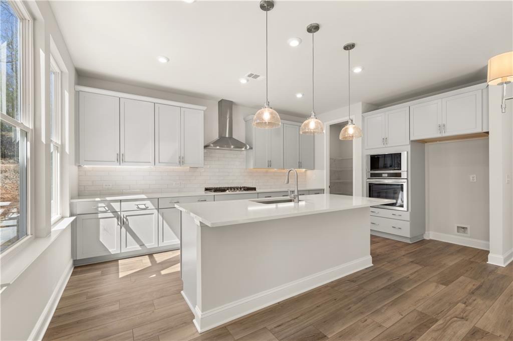 900 Melody Ridge Lane Buford, GA 30518 - Photo 14 of 30 a kitchen with kitchen island a stove a sink a refrigerator and white cabinets with wooden floor