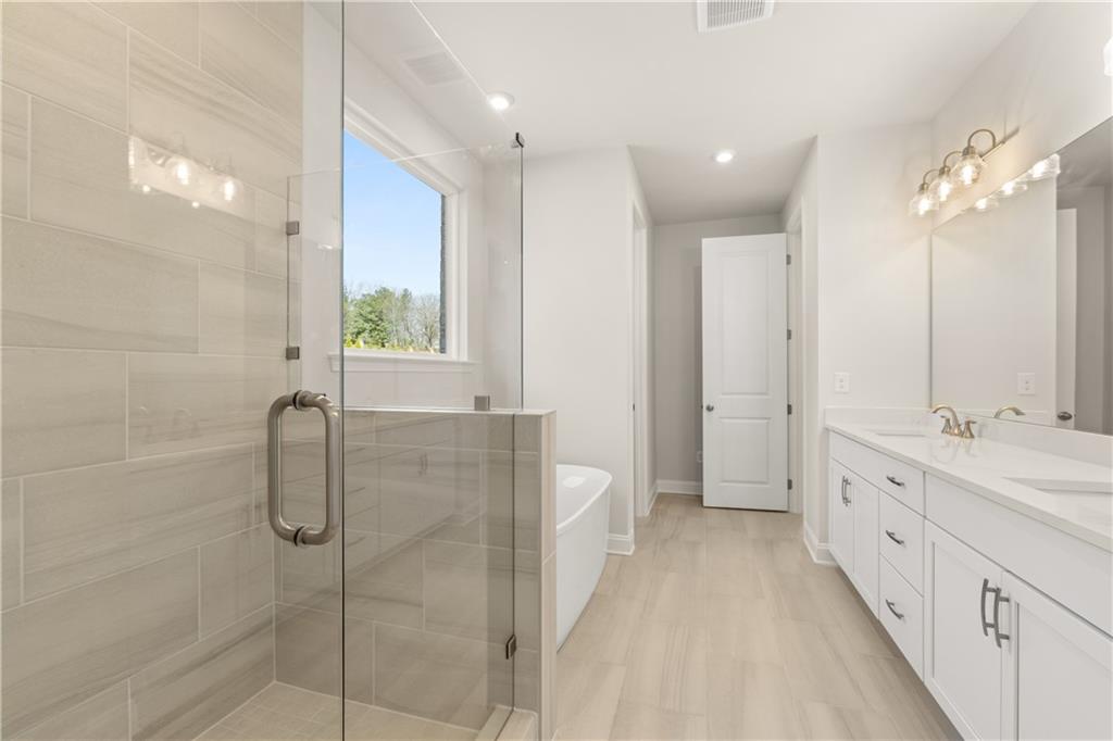 900 Melody Ridge Lane Buford, GA 30518 - Photo 21 of 30 a spacious bathroom with a double vanity sink a large mirror and shower