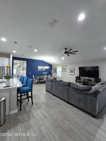 a living room with furniture kitchen view and a chandelier