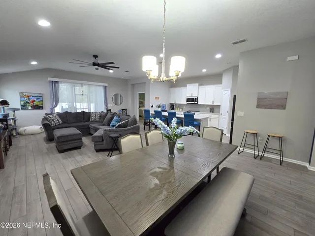 a kitchen with stainless steel appliances a sink a stove a refrigerator cabinets and a dining table