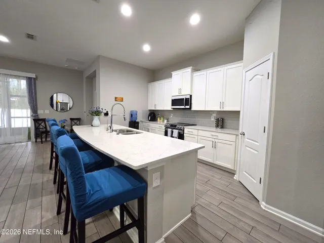 a kitchen with stainless steel appliances granite countertop a table chairs sink refrigerator and cabinets