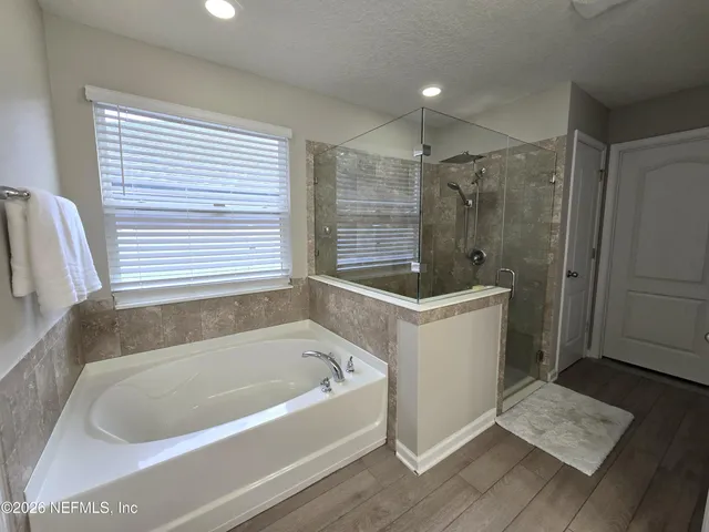 a view of a hallway with wooden floor and a bathroom