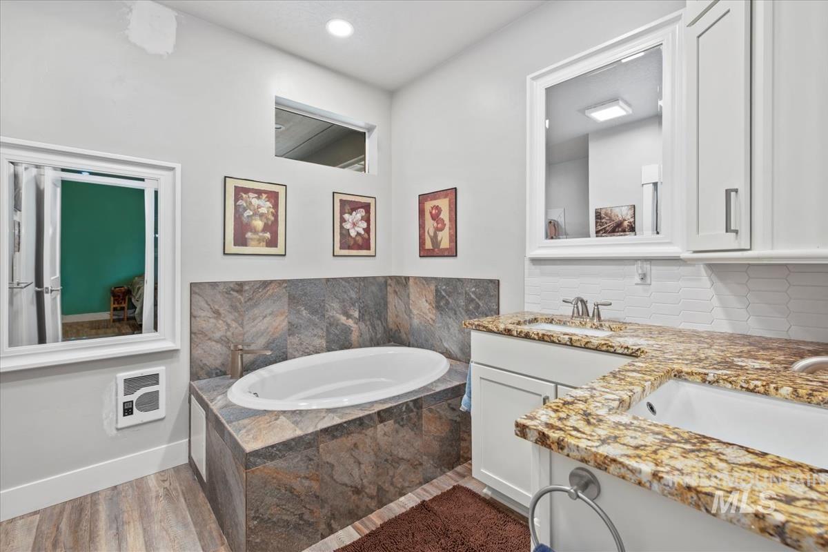 17322 Can-Ada Road Nampa, ID 83687 - Photo 27 of 44 Full bathroom with a garden tub, double vanity, heating unit, and dark wood-type flooring