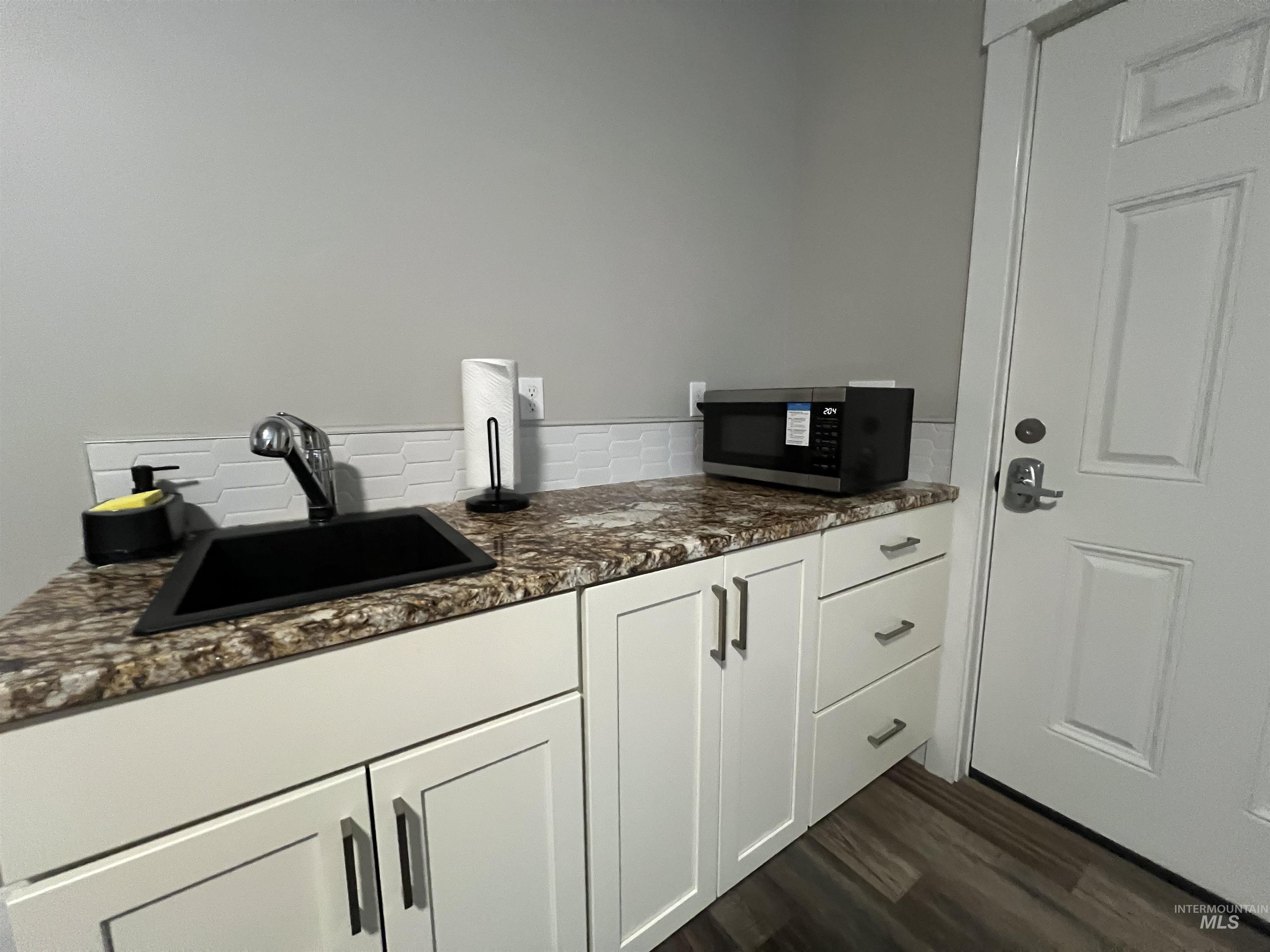 17322 Can-Ada Road Nampa, ID 83687 - Photo 40 of 44 Bar featuring white cabinets, dark stone countertops, stainless steel microwave, dark wood-style floors, and decorative backsplash