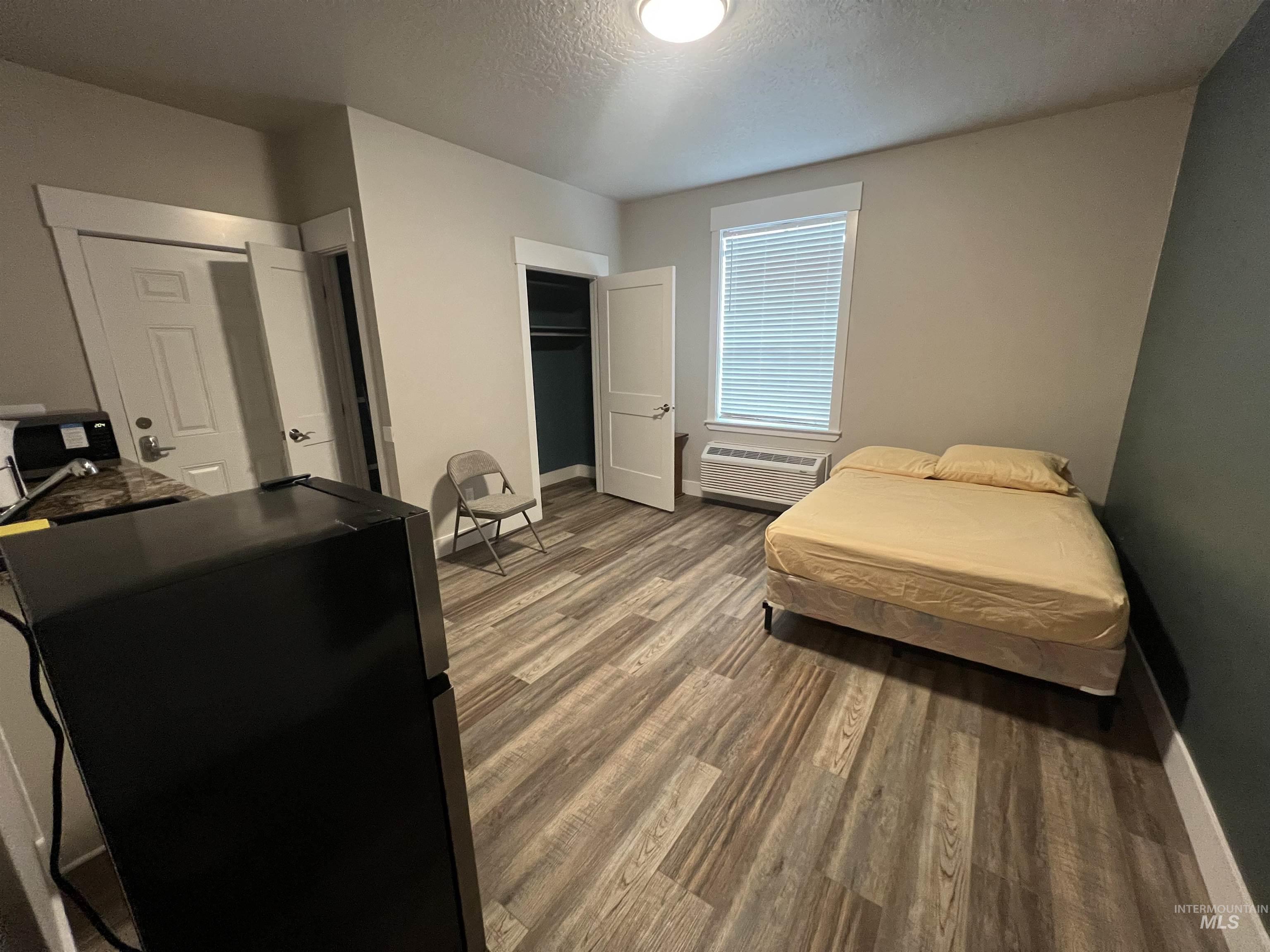 17322 Can-Ada Road Nampa, ID 83687 - Photo 43 of 44 Bedroom featuring a textured ceiling, light wood finished floors, freestanding refrigerator, and an AC wall unit