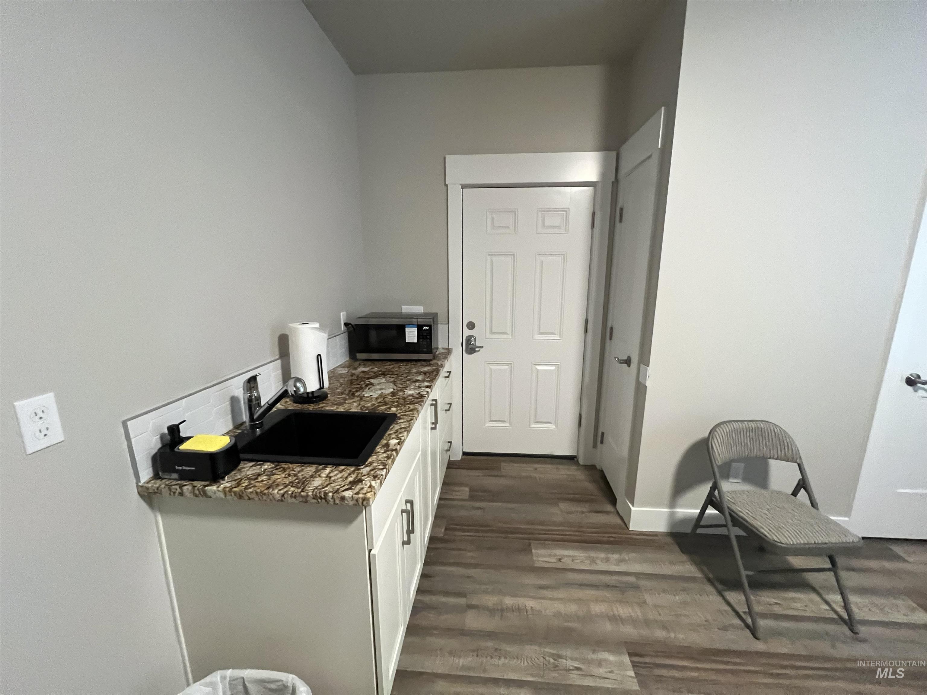 17322 Can-Ada Road Nampa, ID 83687 - Photo 44 of 44 Kitchen with white cabinetry, dark stone counters, stainless steel microwave, and dark wood-style flooring