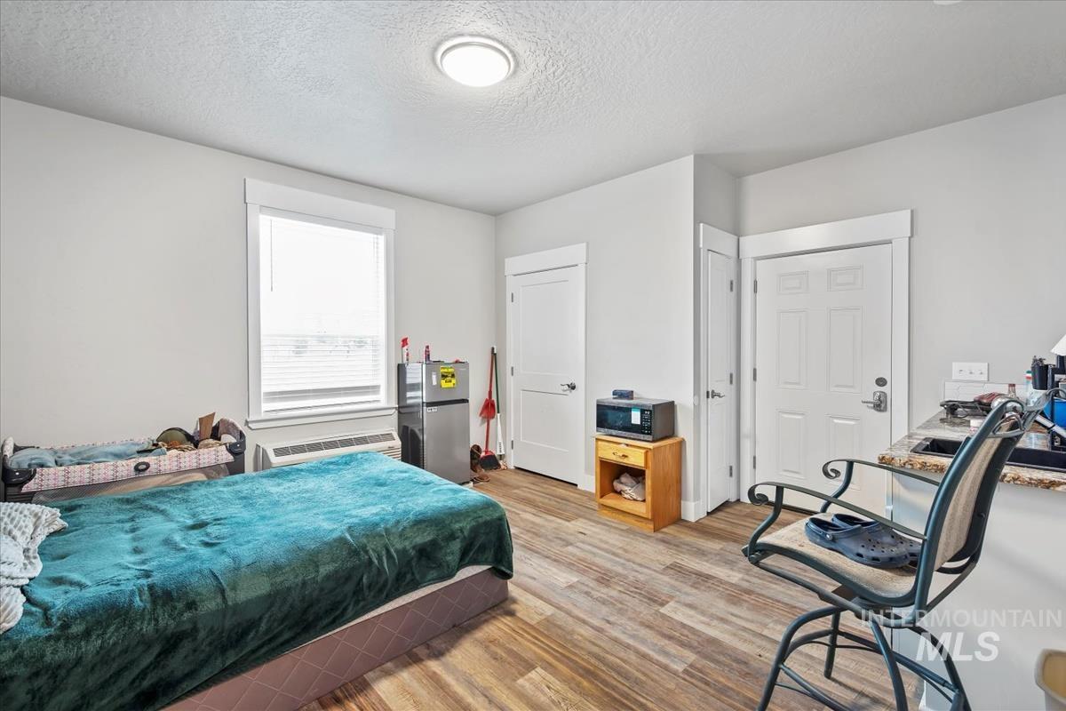 17322 Can-Ada Road Nampa, ID 83687 - Photo 8 of 44 Bedroom featuring a textured ceiling, light wood finished floors, freestanding refrigerator, and a wall mounted AC