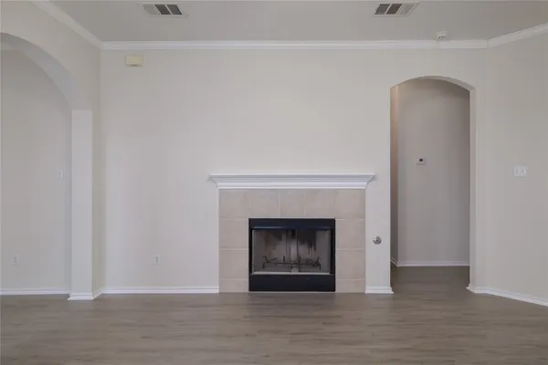 a view of an empty room with wooden floor and a fireplace