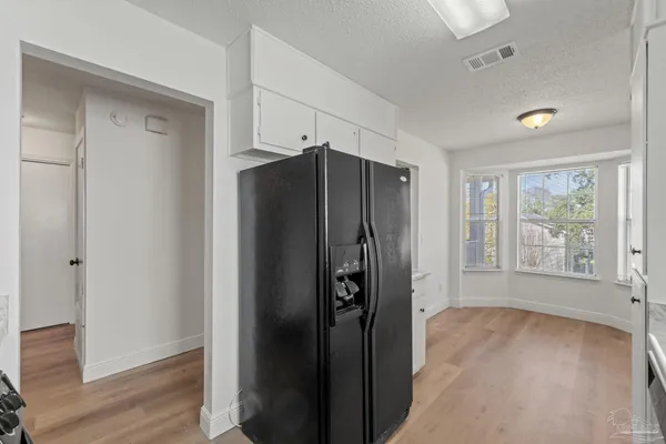 a view of a refrigerator in kitchen and wooden floor in an empty room